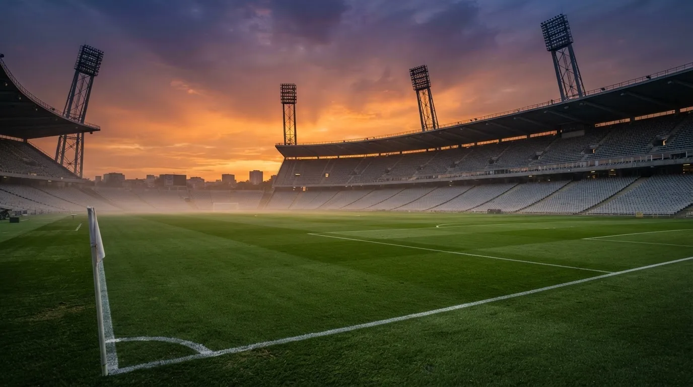 Un estadio de fútbol vacío con torres de iluminación al atardecer