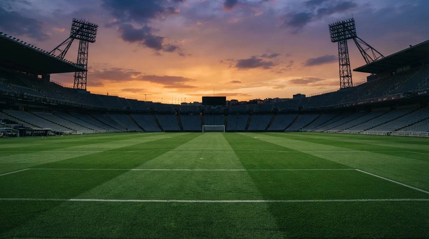 Un estadio de fútbol vacío con torres de iluminación al atardecer