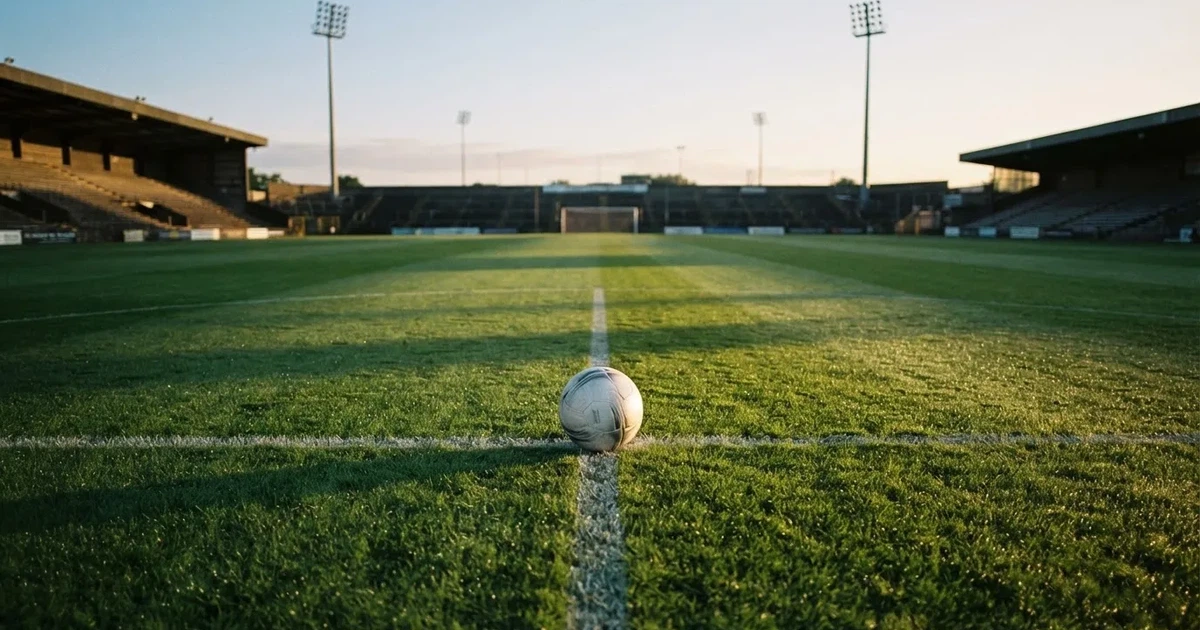 Un balón en el punto central de un campo de césped a la luz de la mañana