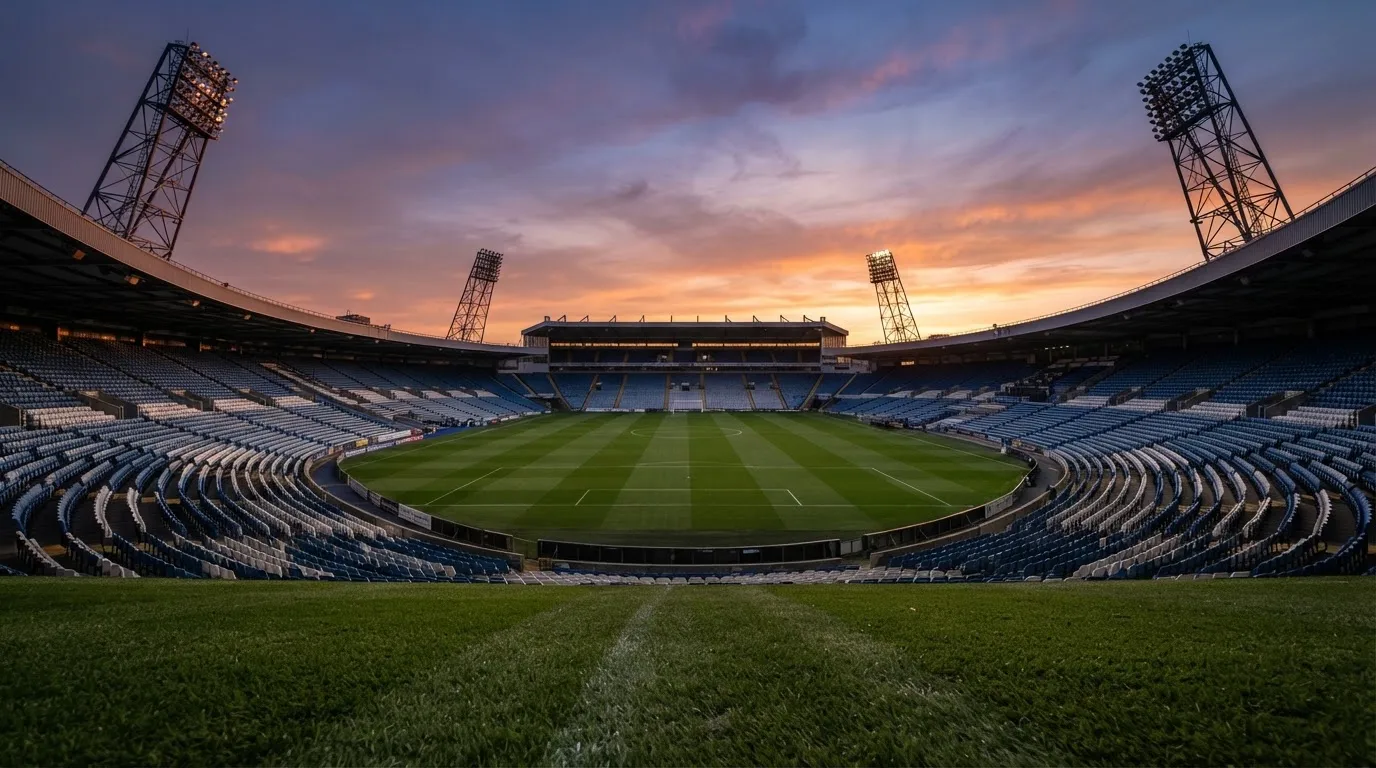 Un estadio de fútbol vacío con torres de iluminación al atardecer