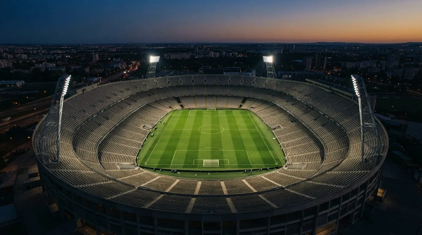 Un estadio de fútbol vacío con torres de iluminación al atardecer