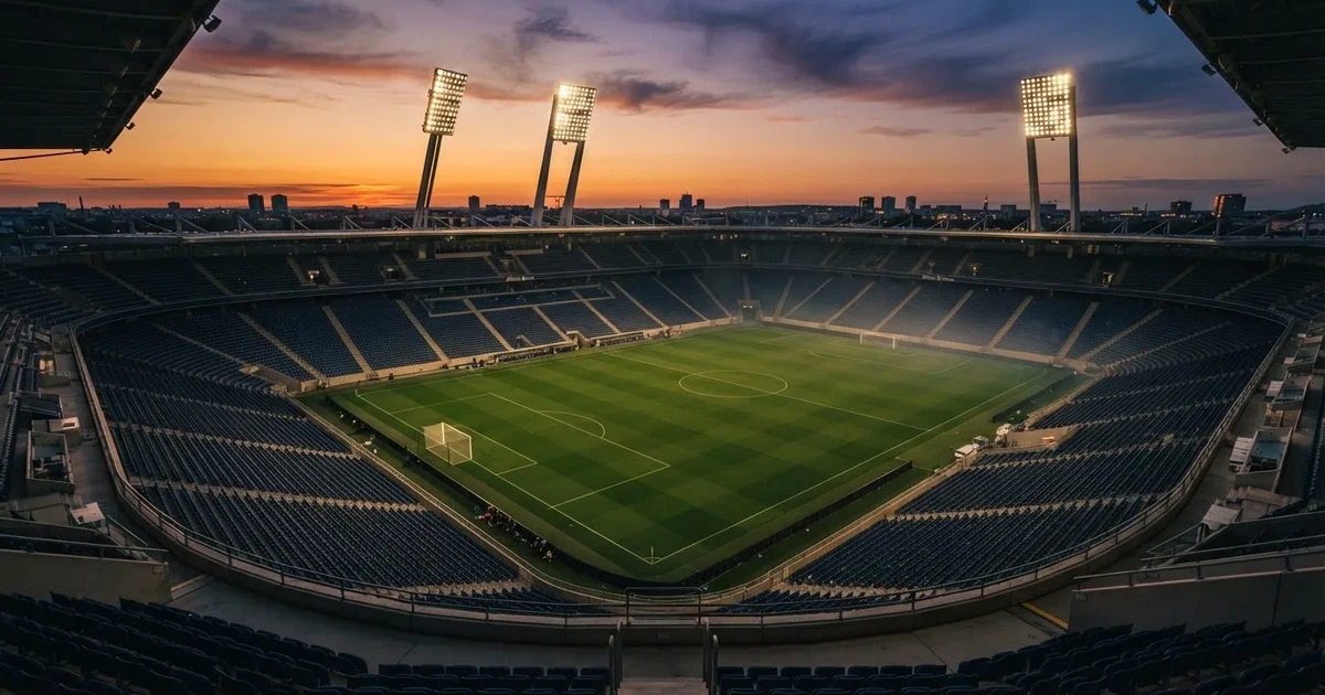 Un estadio de fútbol vacío con torres de iluminación al atardecer